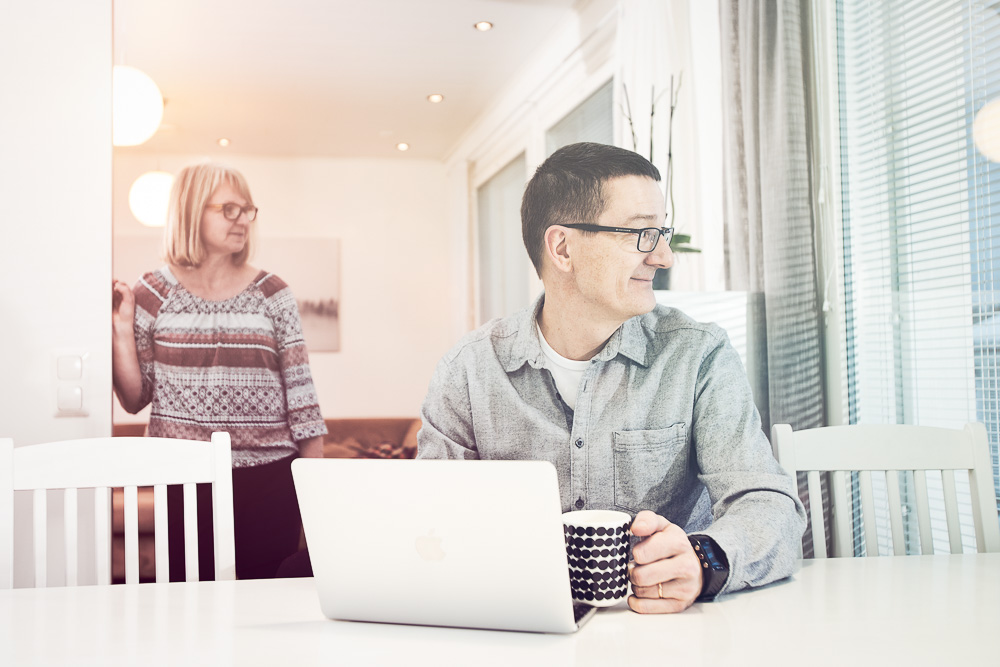 Mies istuu keittiönpöydän ääressä ja tutkii tietokoneelta sähkönkäyttöään.