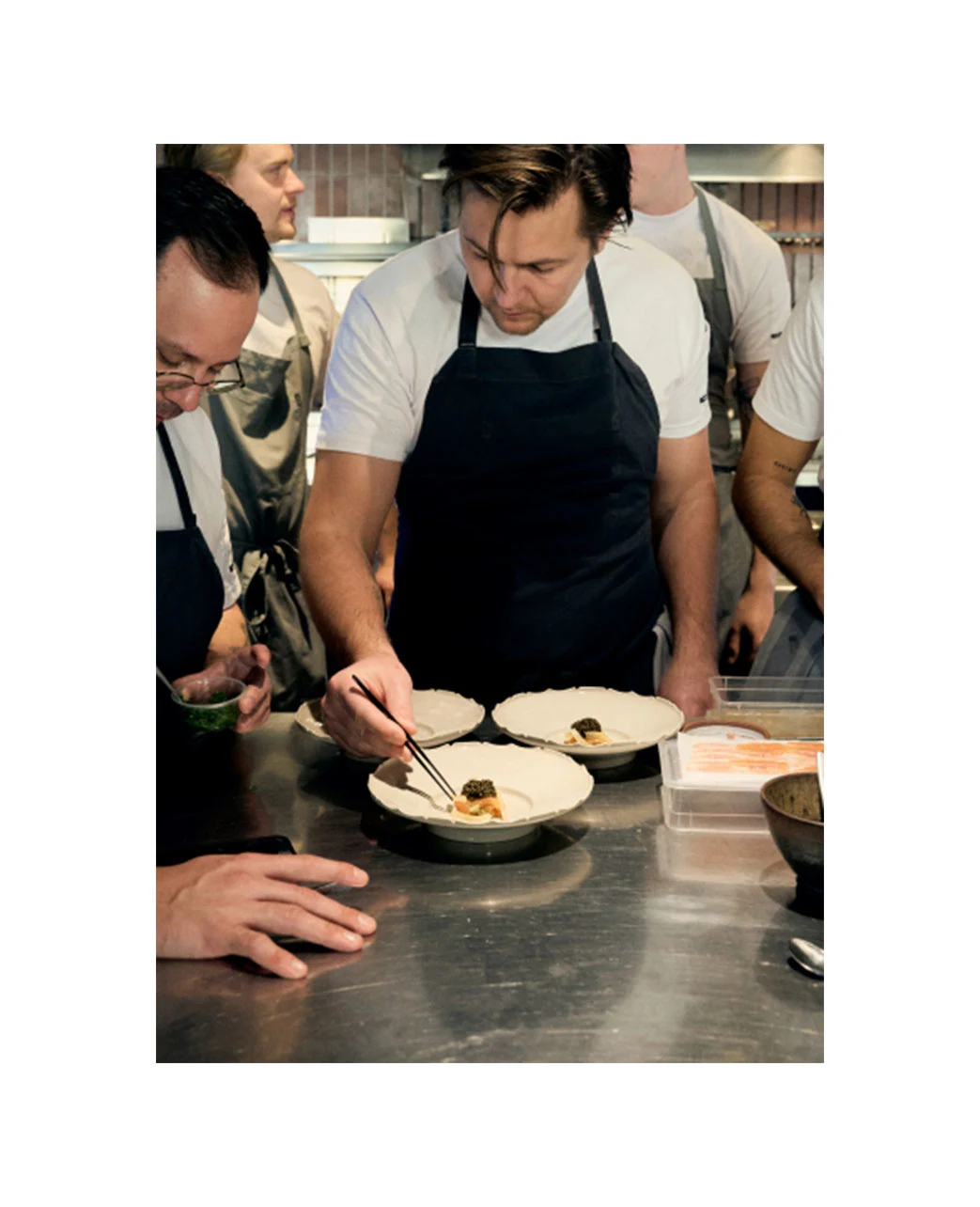 chefs in a professional kitchen plating high end dishes