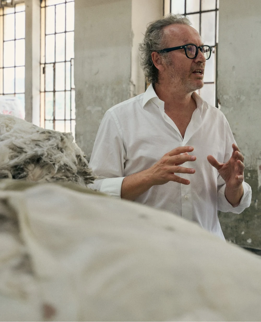 an older man talking about wool fabric in a production unit