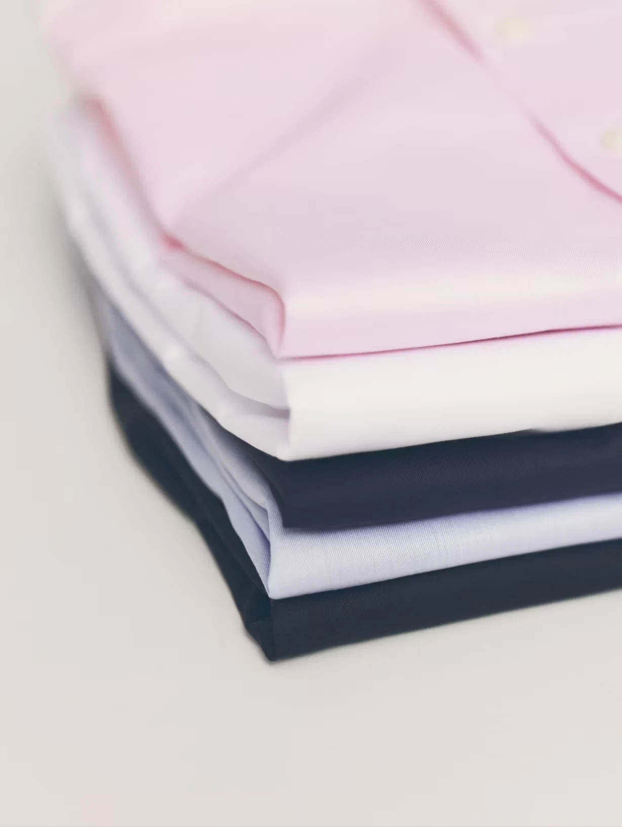 several folded signature twill shirts in a pile