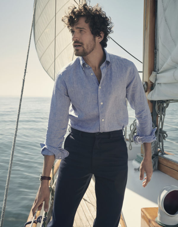 man on a boat wearing a light blu linen shirt