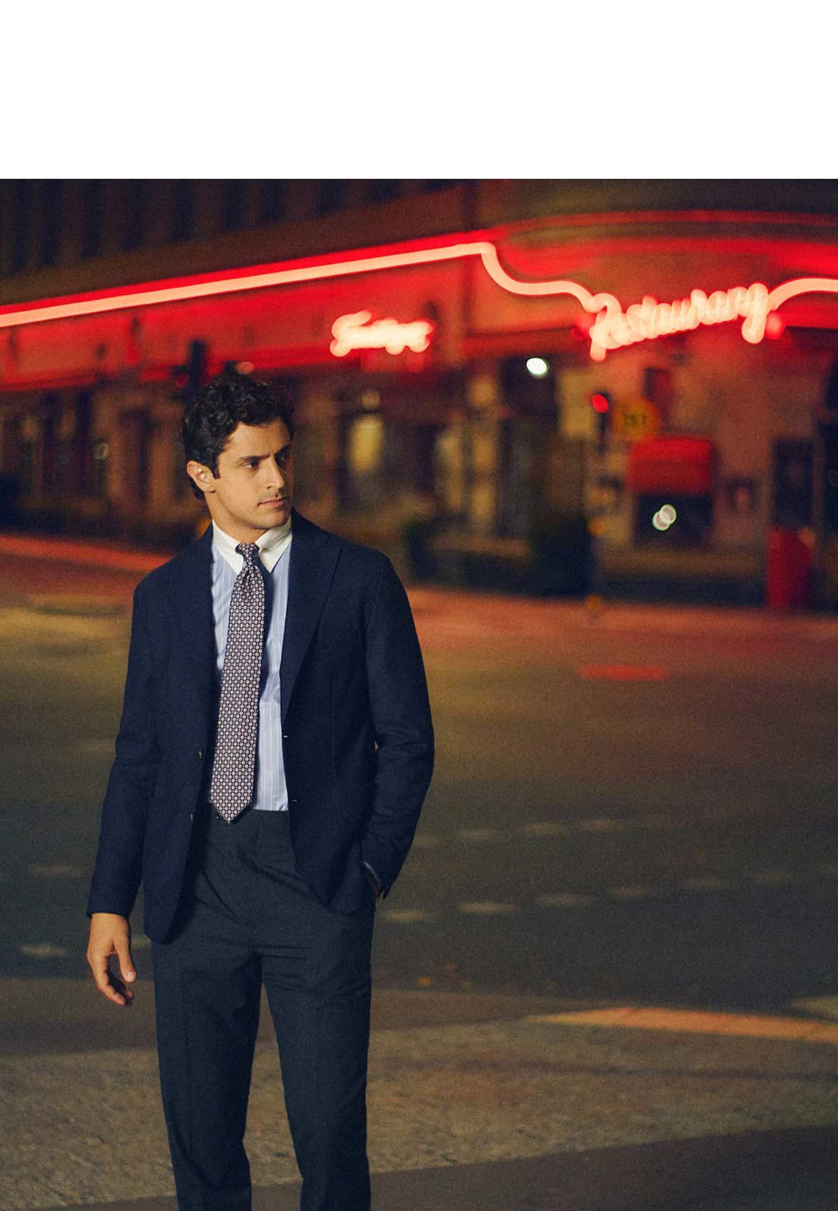 a man posing during the night in the city with neon signs in the background