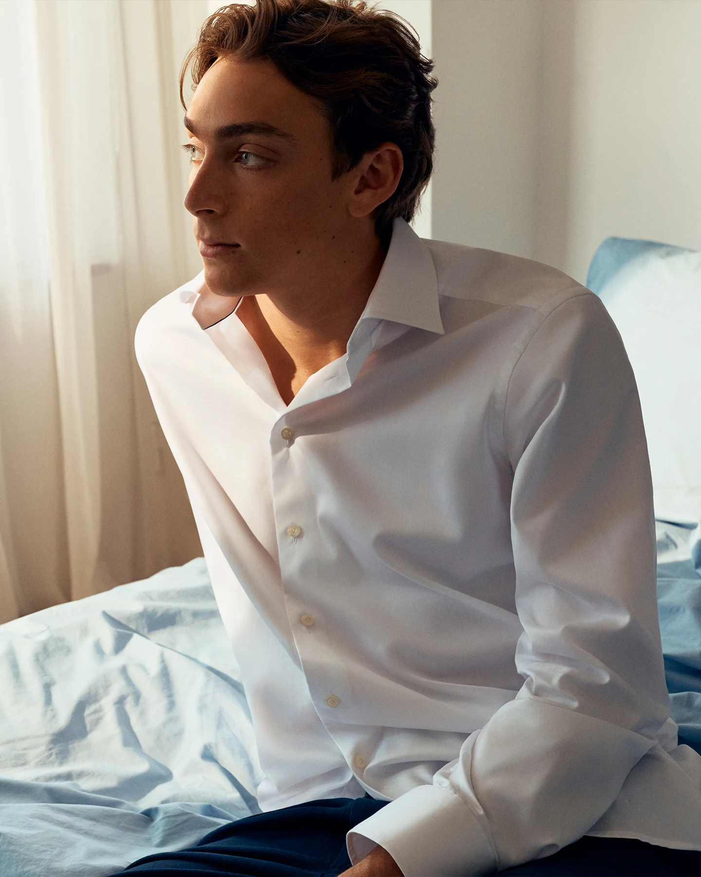 Mondo sitting on a bed with a white shirt