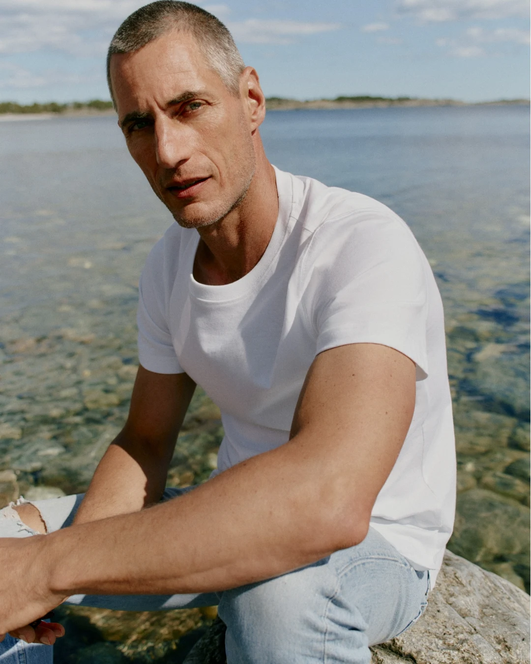 modell sitting on the beach with an white t-shirt