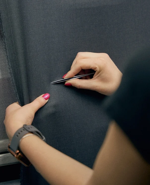 a woman inspecting a piece of fabric with a tweezer
