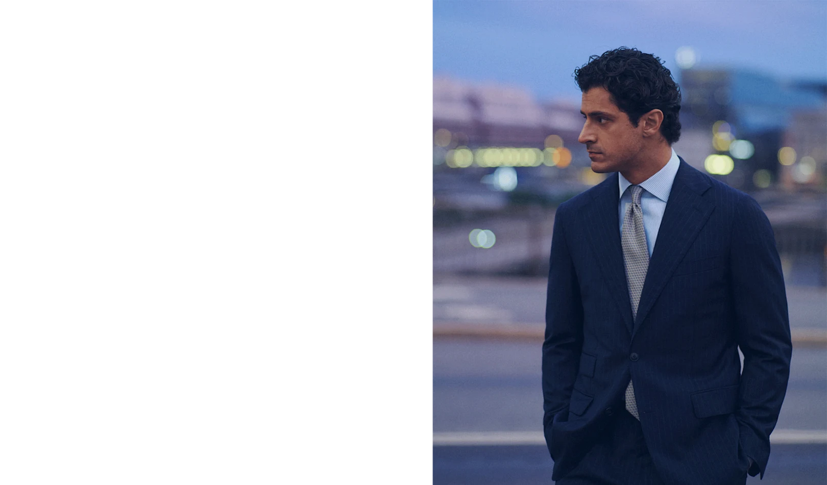 a man posing in a light blue signature twill shirt and a navy soft jacket in the evening in a city