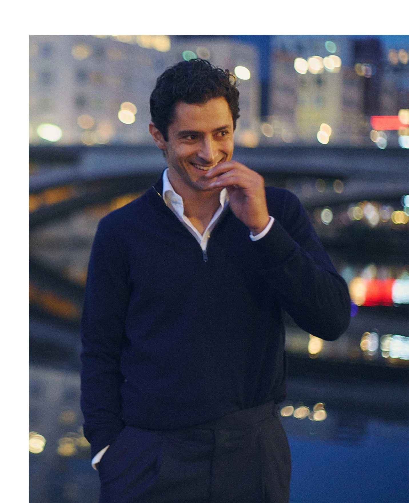 a guy posing with white signature twill shirt and a navy quarter zip sweater in the city during the evening setting