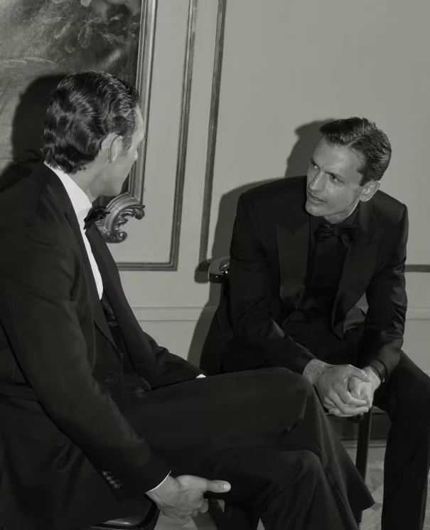 black and white photo of two men sitting on chairs engaging conversation