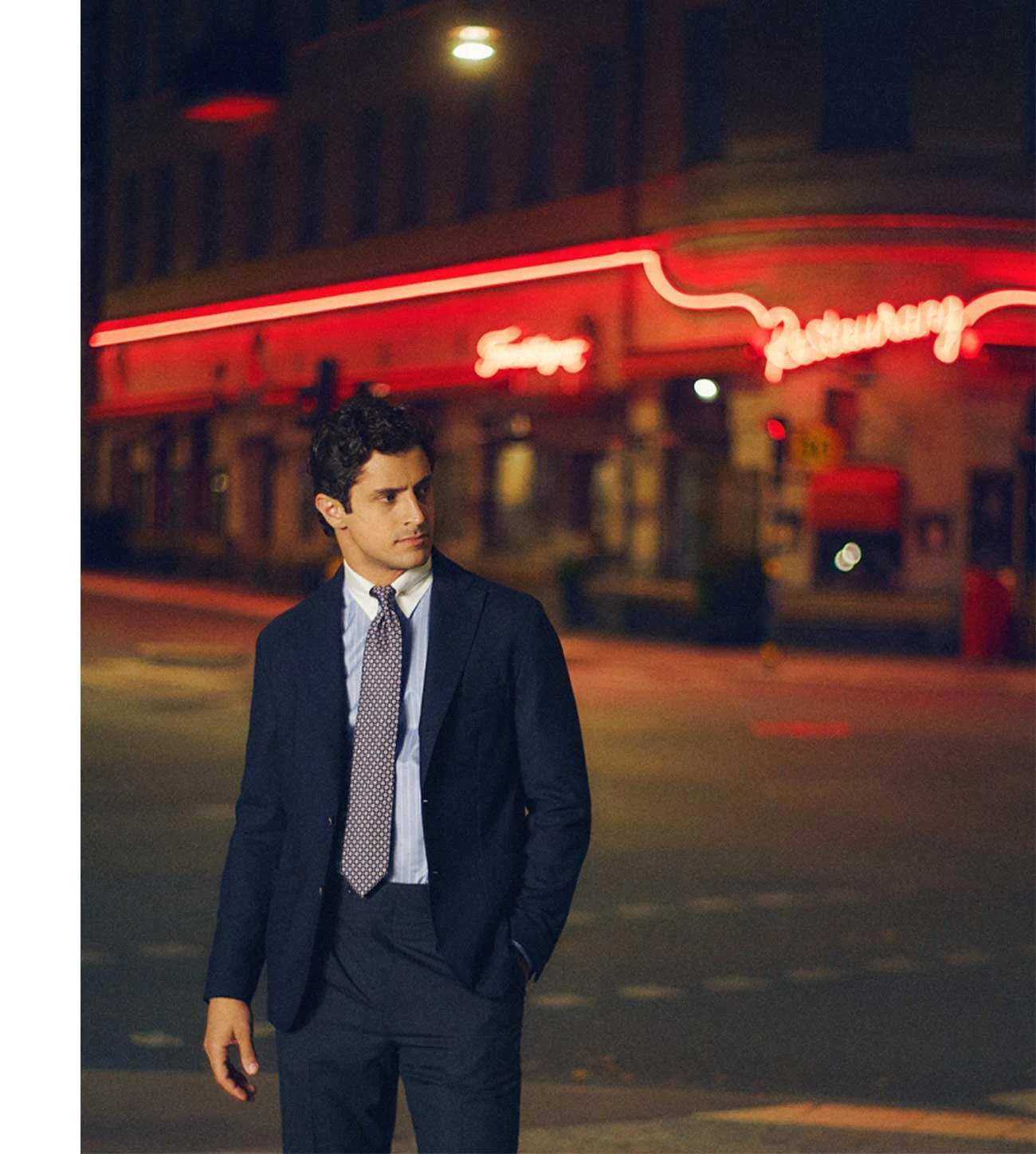 a man standing by a bridge in a city smiling with a white signature twill shirt and a navy quarter zip merino sweater