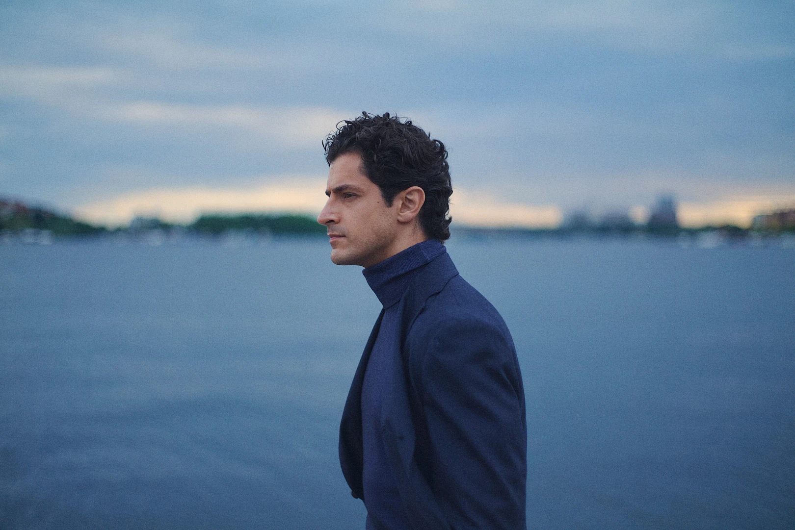A man posing in a blue signature twill shirt and a navy striped grenadine tie