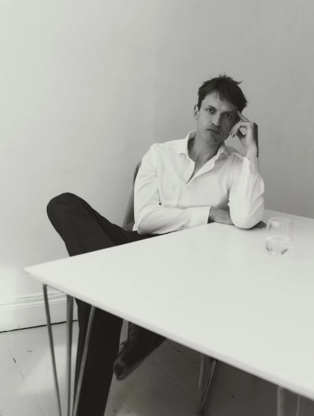 a man sitting on a chair leaning on a table posing in a white filo di scozia shirt