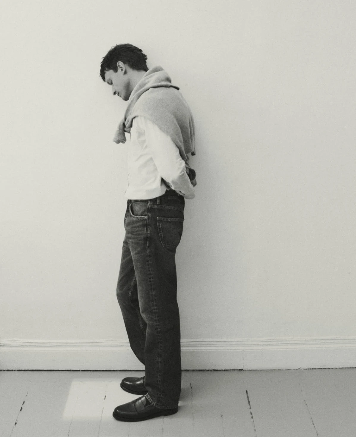man standing in a room looking down in a eton oxford shirt