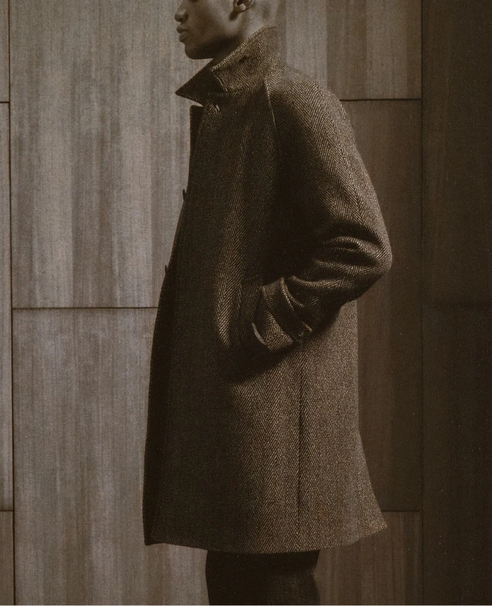 a model wearing the raglan coat shot from the side