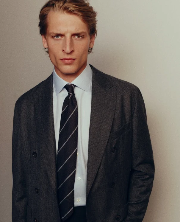 a man posing in a eton shirt, eton soft jacket and tie