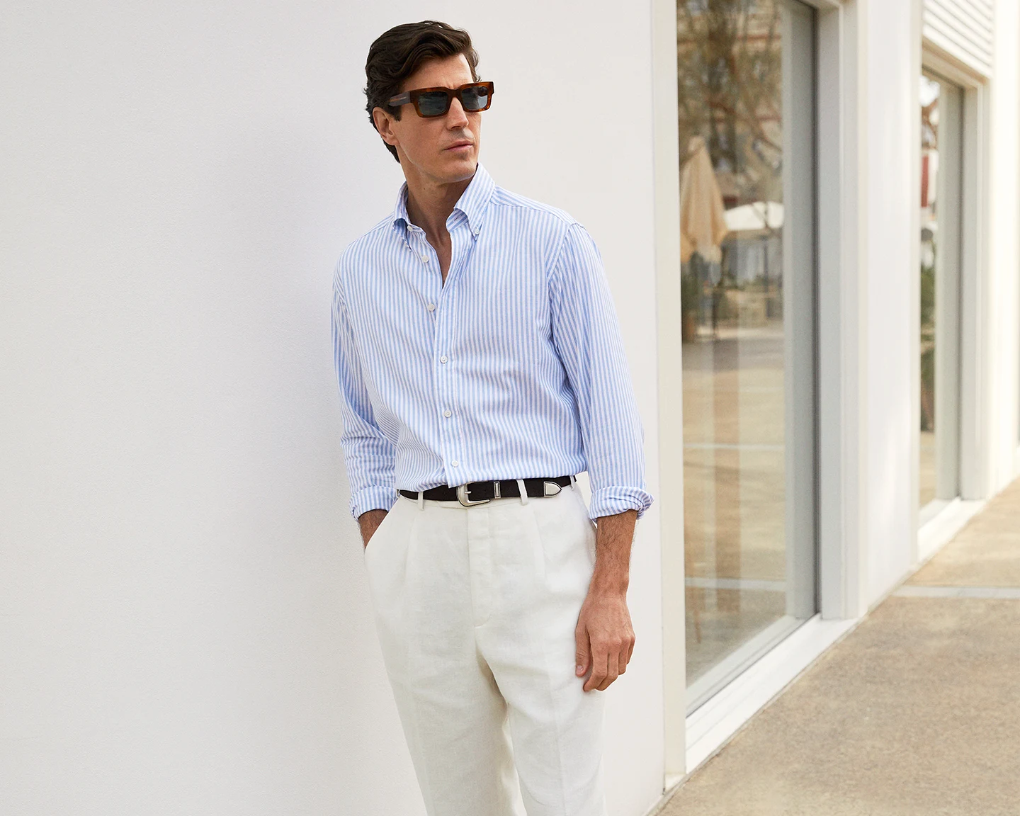 model with white and blue striped oxford shirt and white trousers