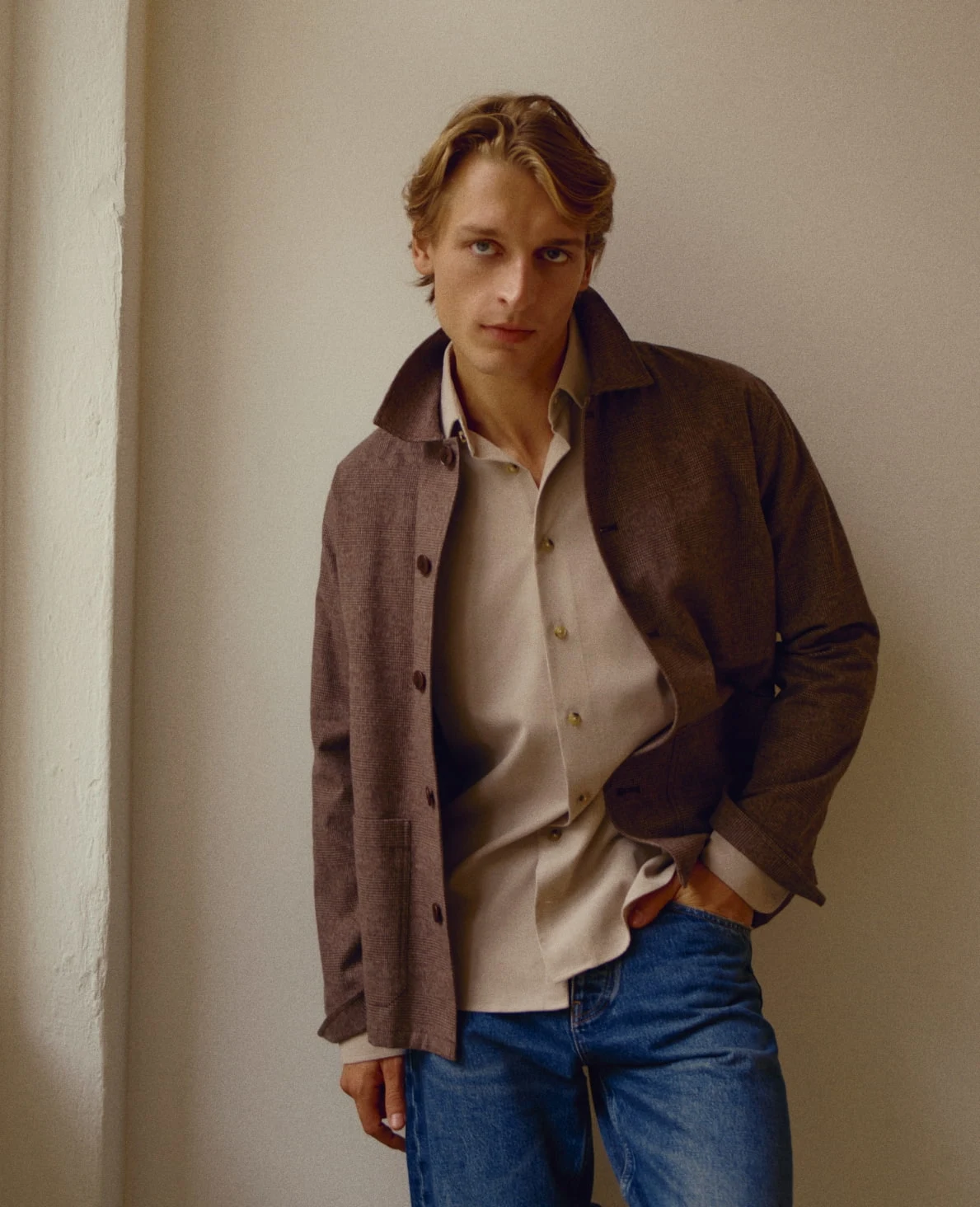 campaign image of a model posing in a brown overshirt and beige flannel shirt