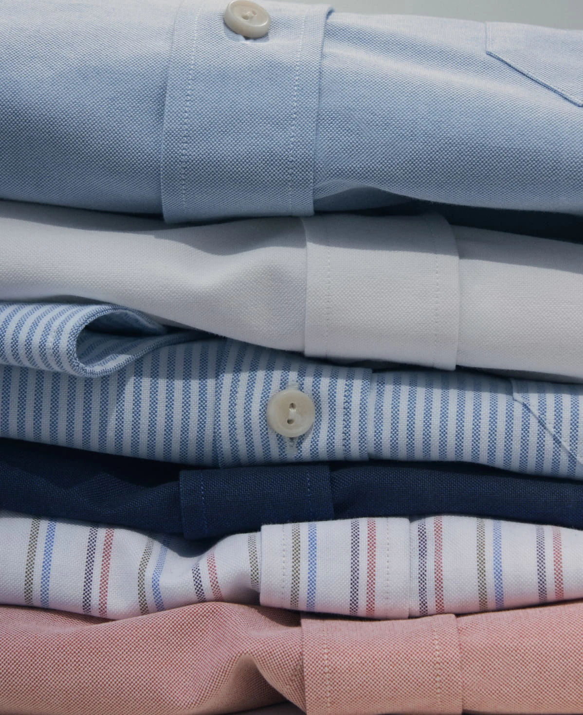 pile of folded eton oxford shirts in different colors and patterns