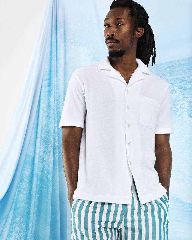 Man wearing green striped swim shorts and a white Terry shirt