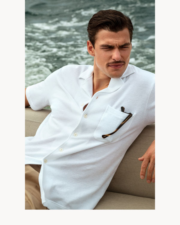 Man wearing a white Eton terry resort shirt on a boat