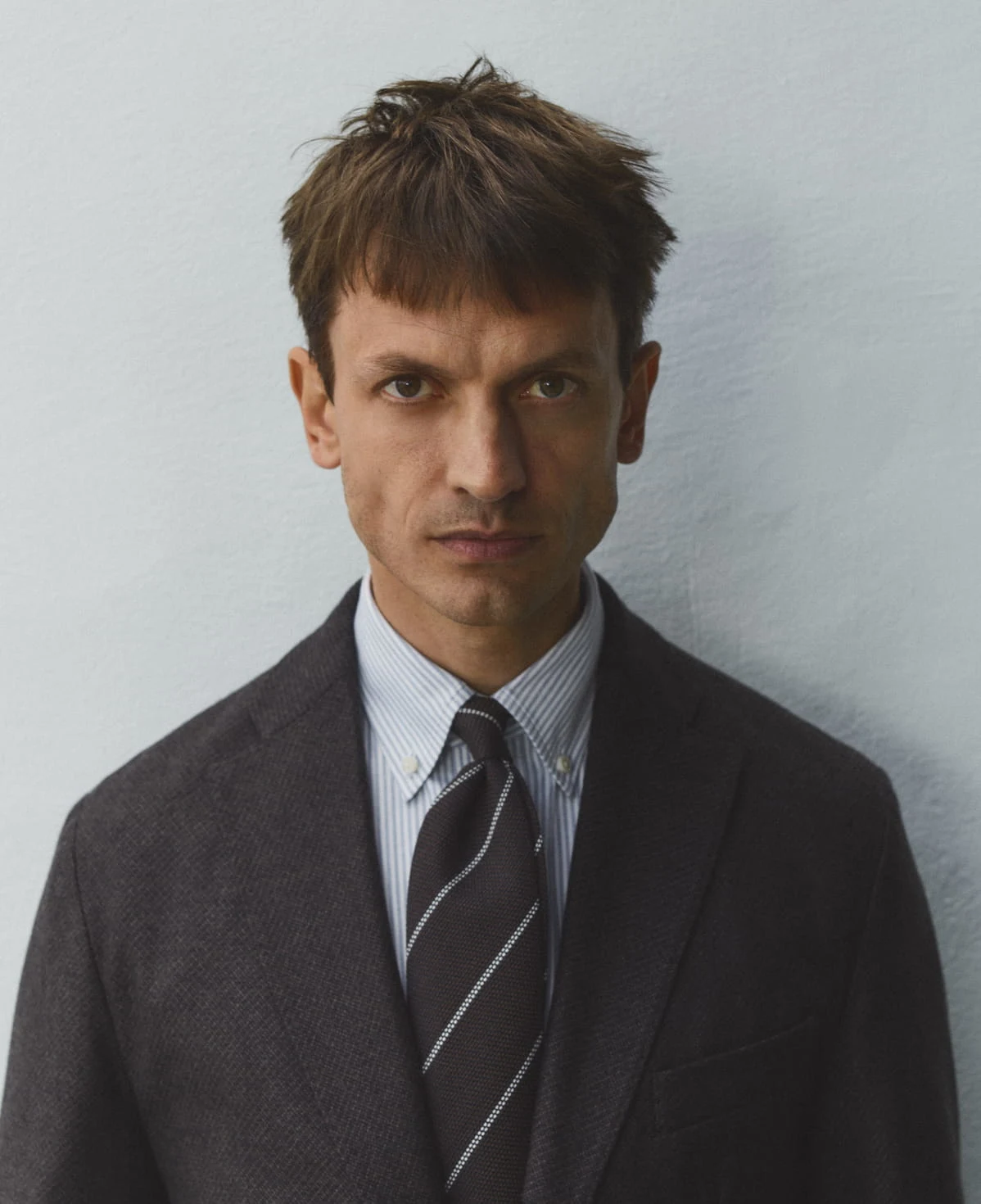 a GIF of a man posing in a oxford shirt in different locations and a pile of eton oxford shirts folded