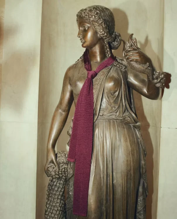 old brass statue wearing a burgundy scarf around the neck