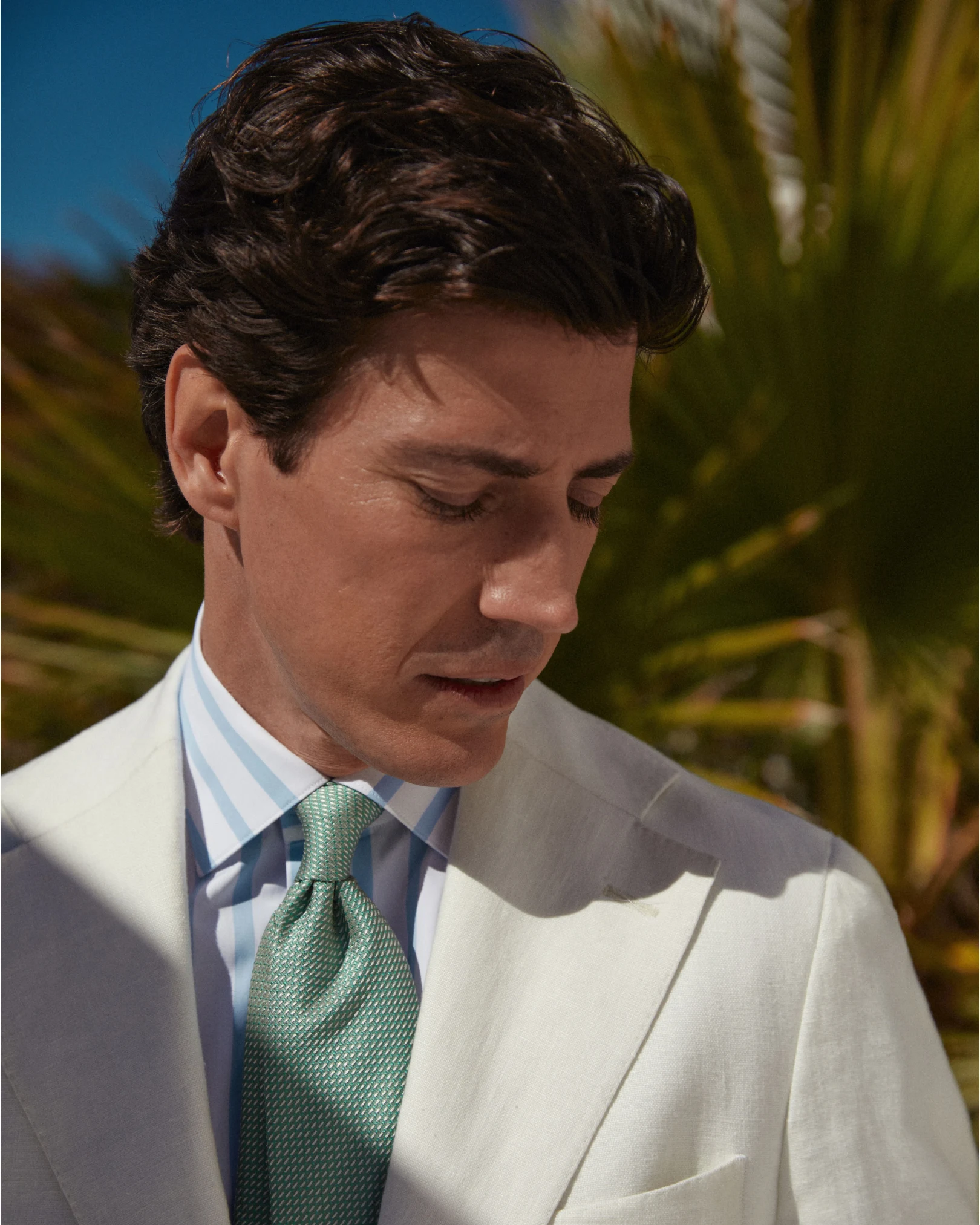 close up beige suit striped shirt and green tie