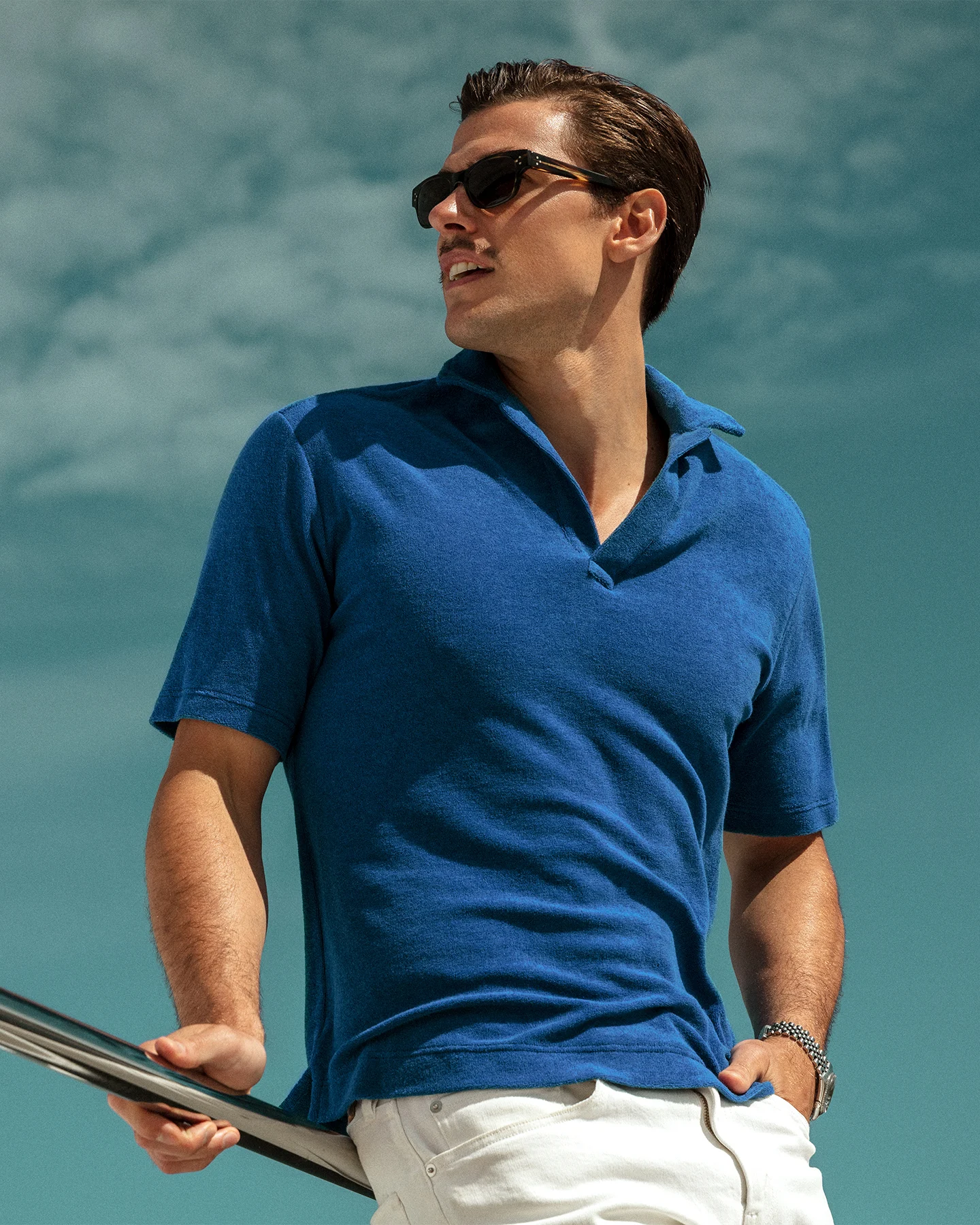 A man wearing the Eton pop-over terry shirt in blue with a pair of white jeans