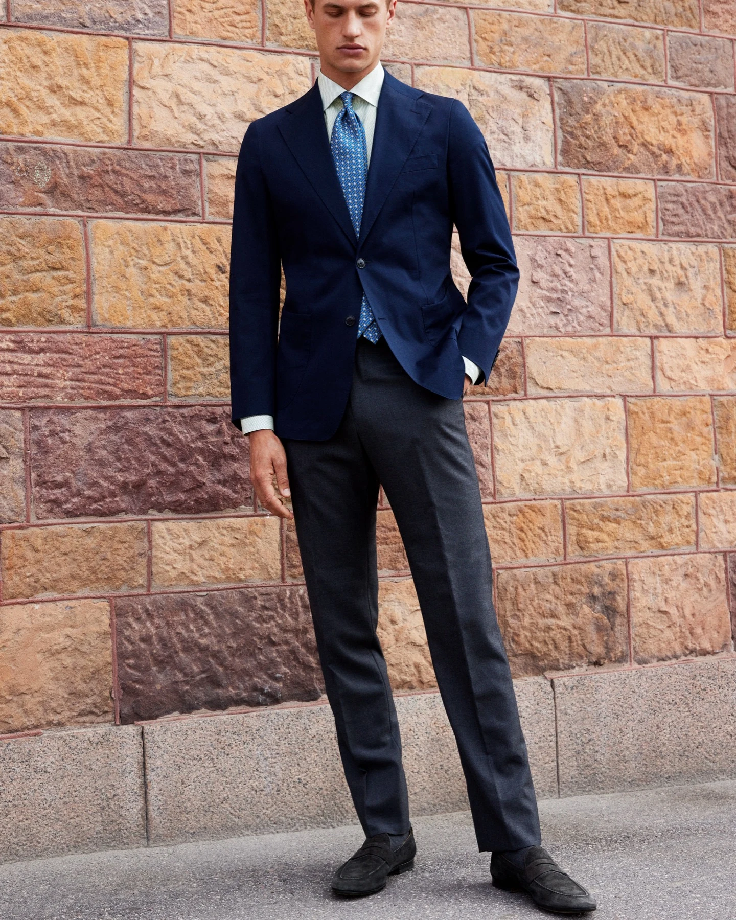 model in suit in front of brick wall