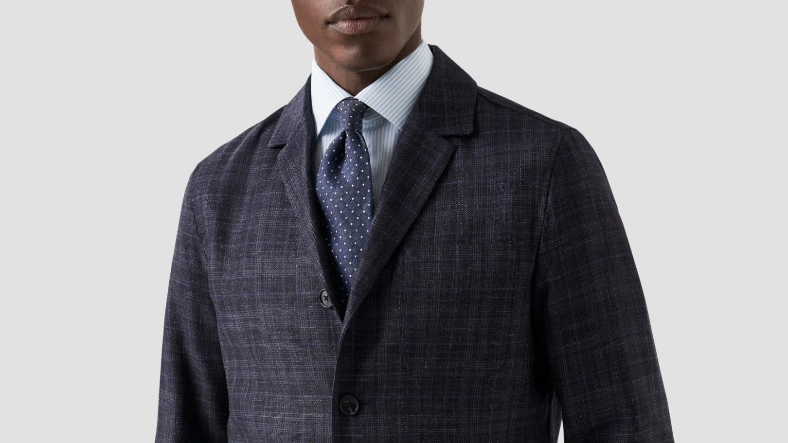 model in dark suit striped shirt and dotted tie