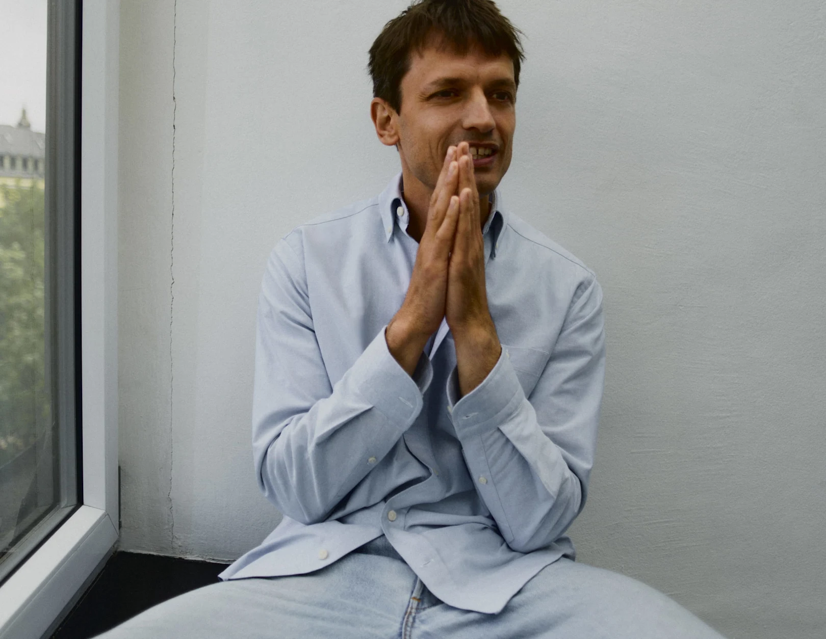 a man posing in a blue oxford shirt
