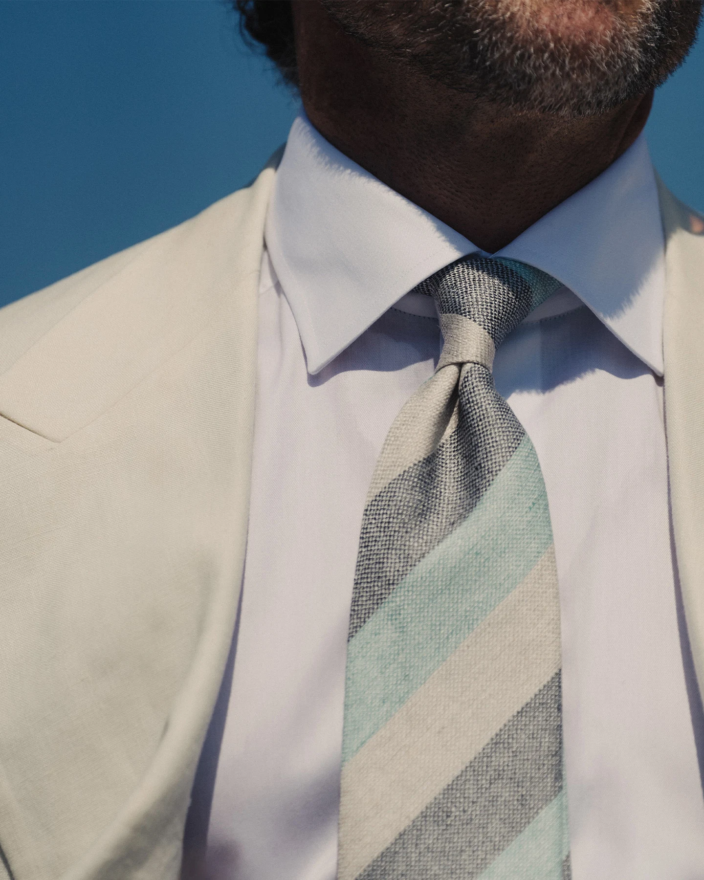 close up striped tie on white shirt and beige suit