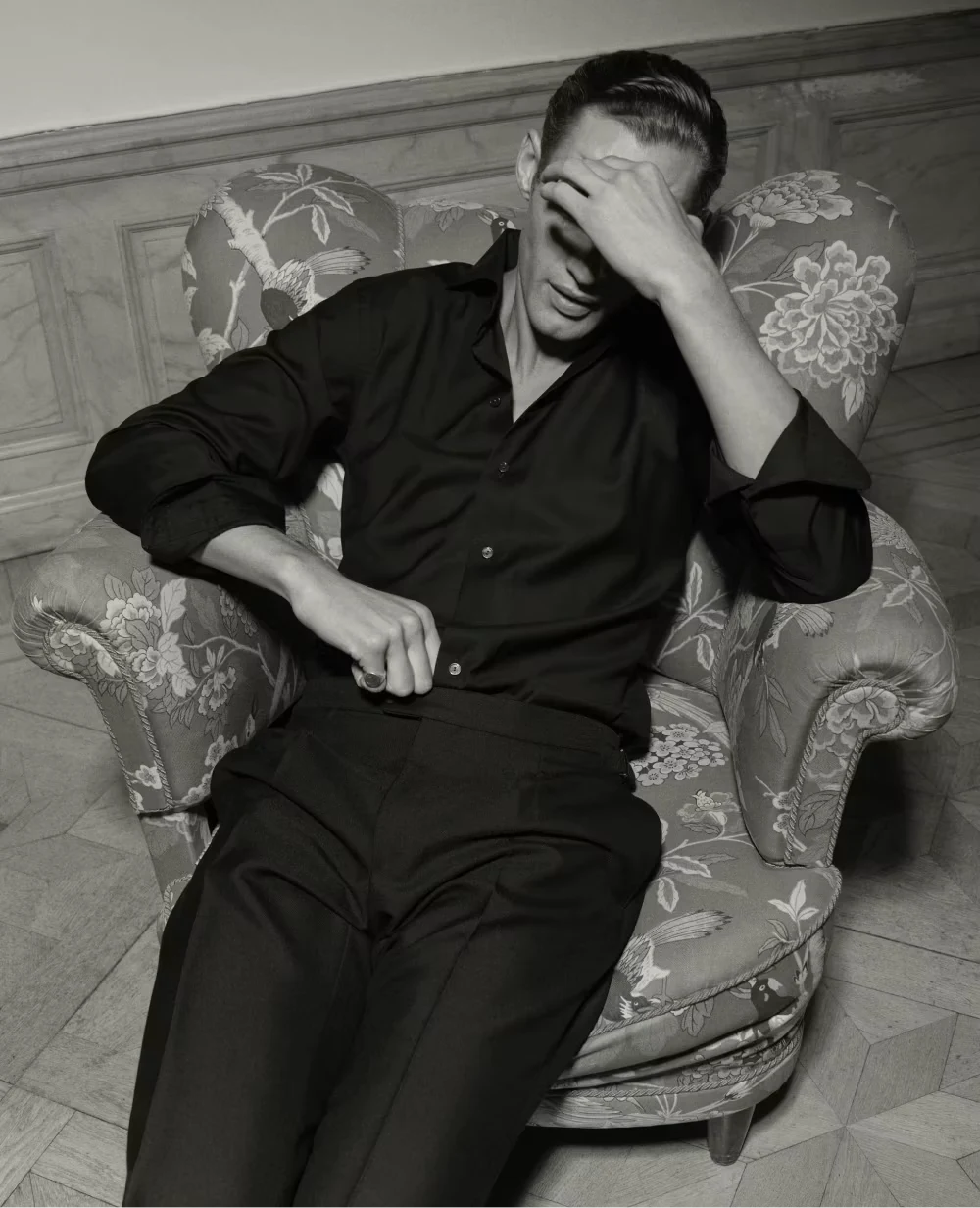 a man in chair with a hand in front of his face wearing a black merino shirt