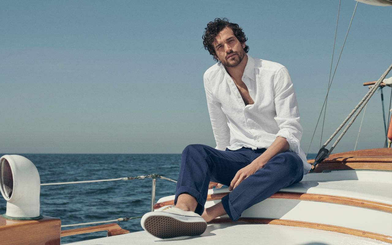 Man sitting on a boat in a white linen shirt
