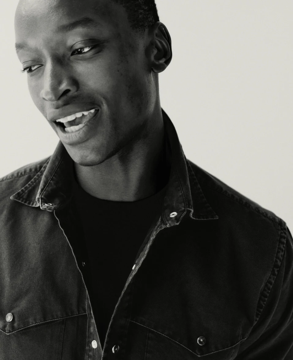 a black and white image of a model in a black denim shirt