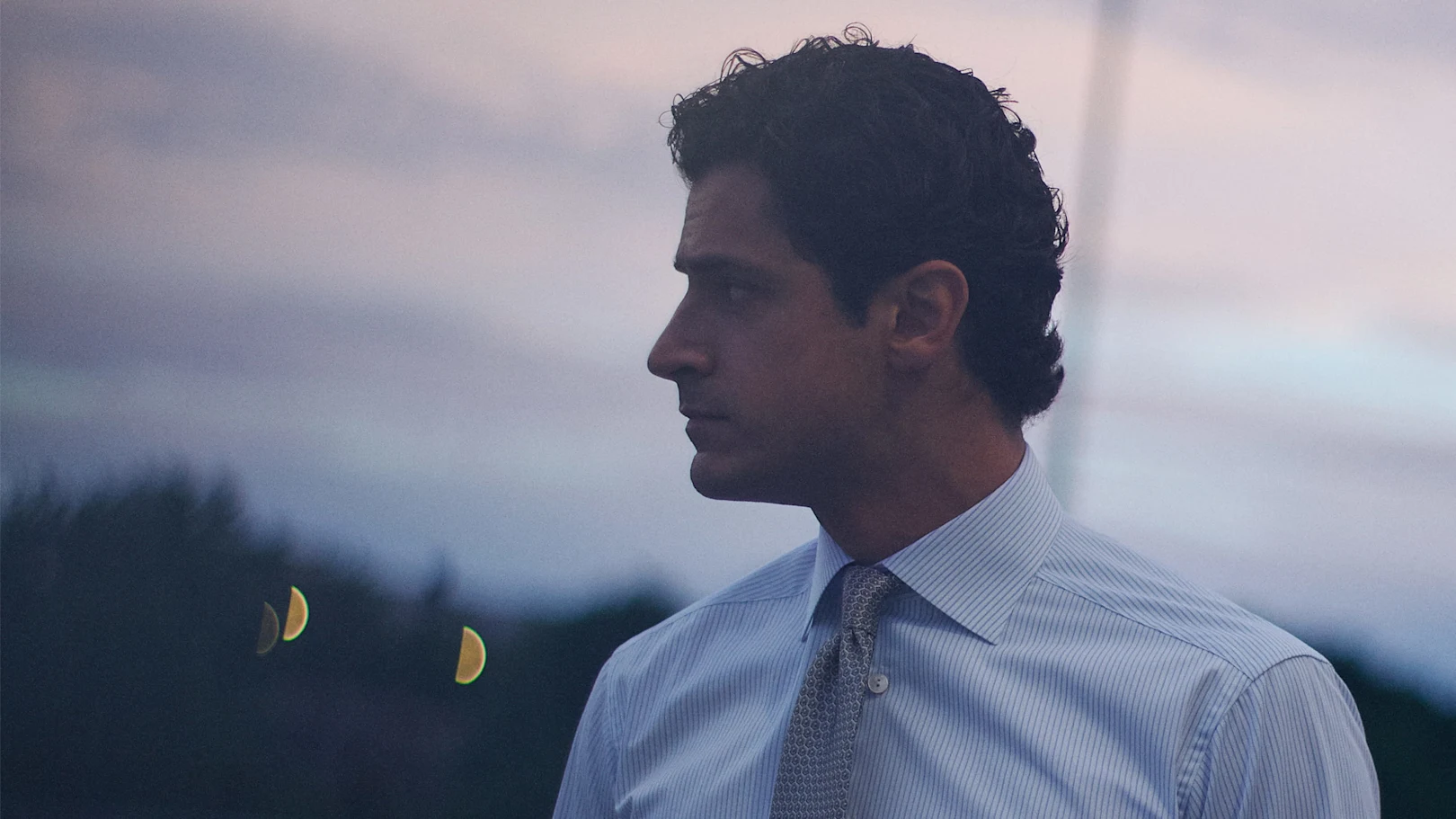 A man posing in a blue signature twill shirt and a navy striped grenadine tie