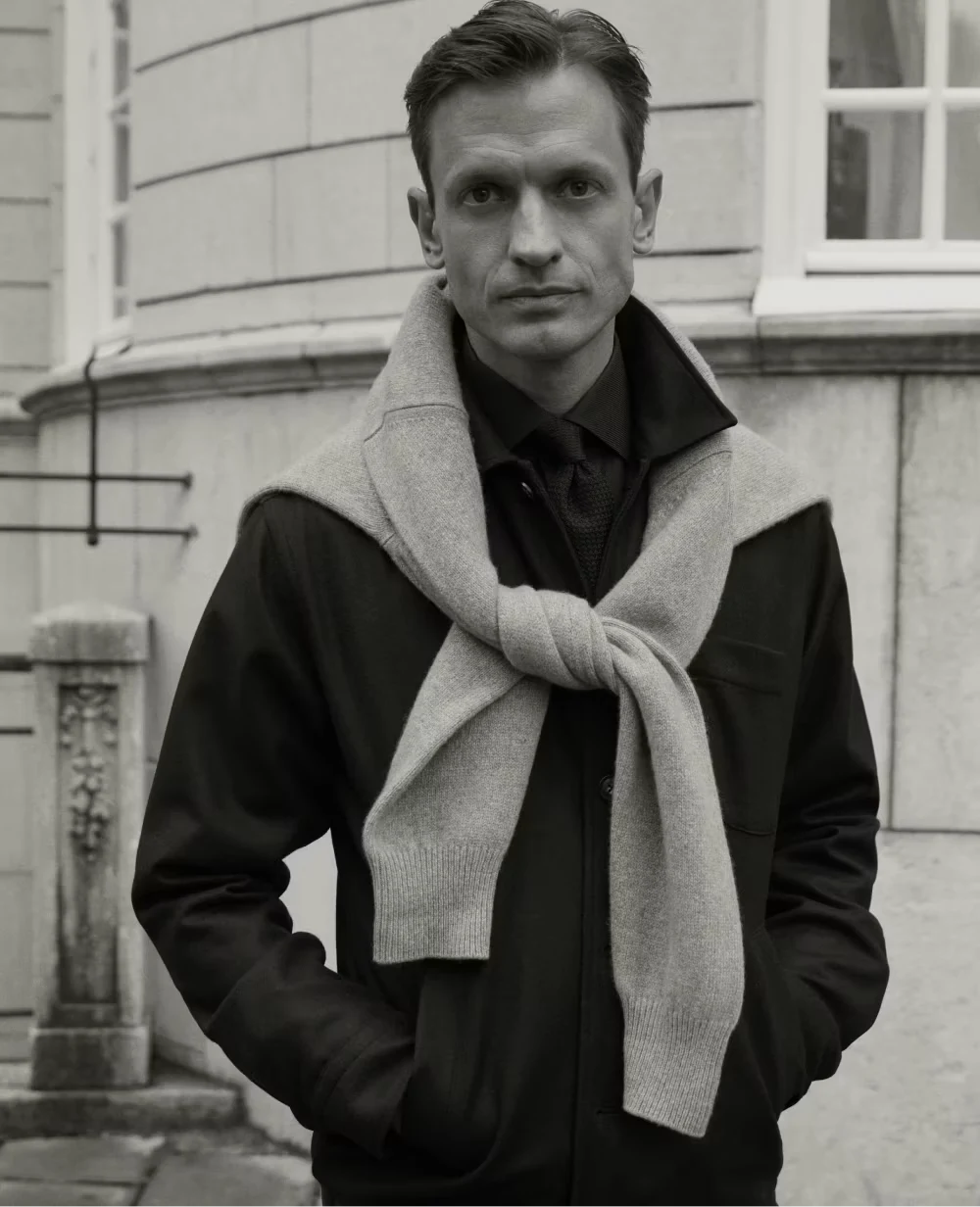 black and white photo of a man posing outside an old building