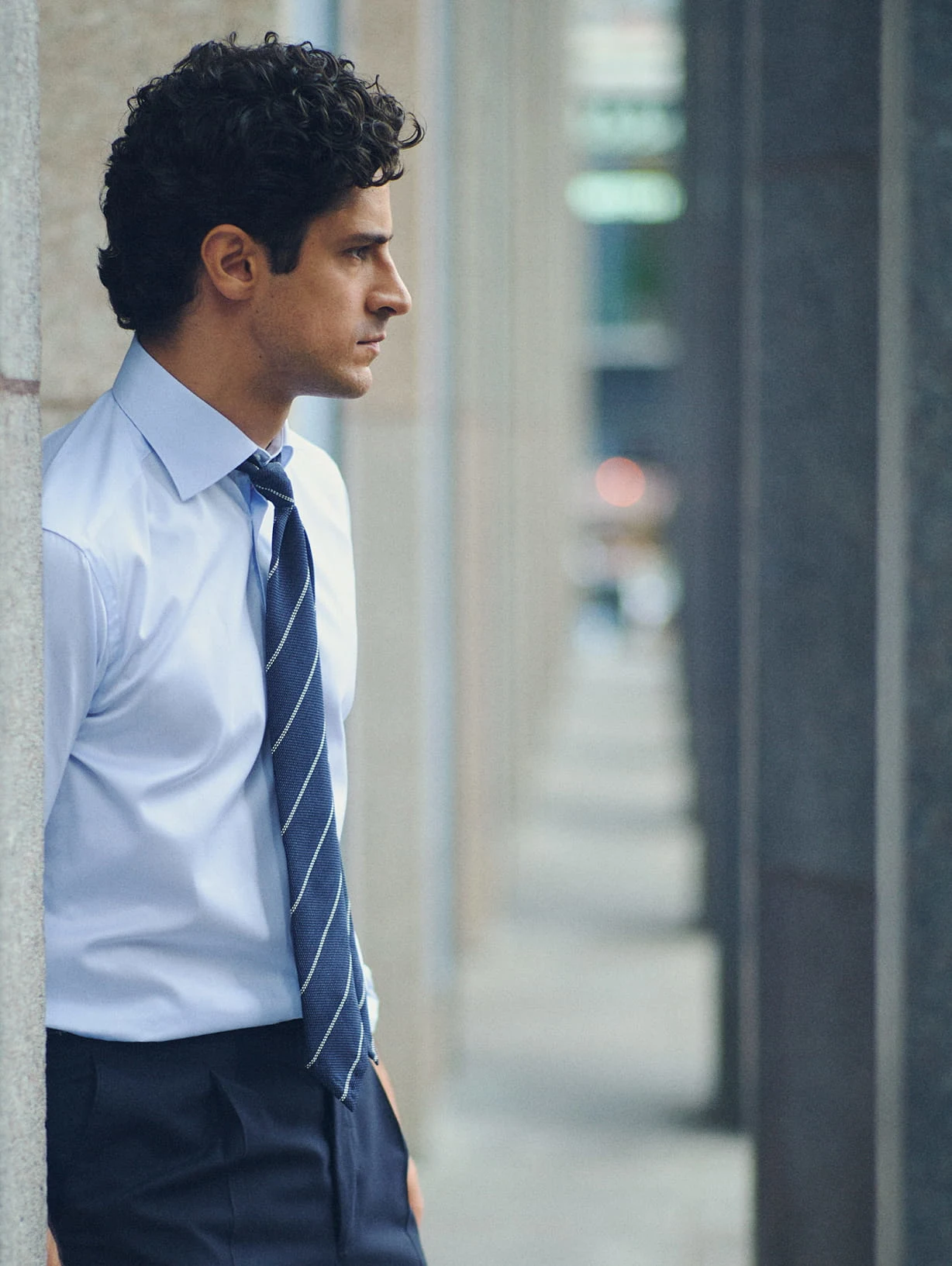 a man in a signature twill blue shirt standing by concrete pillars