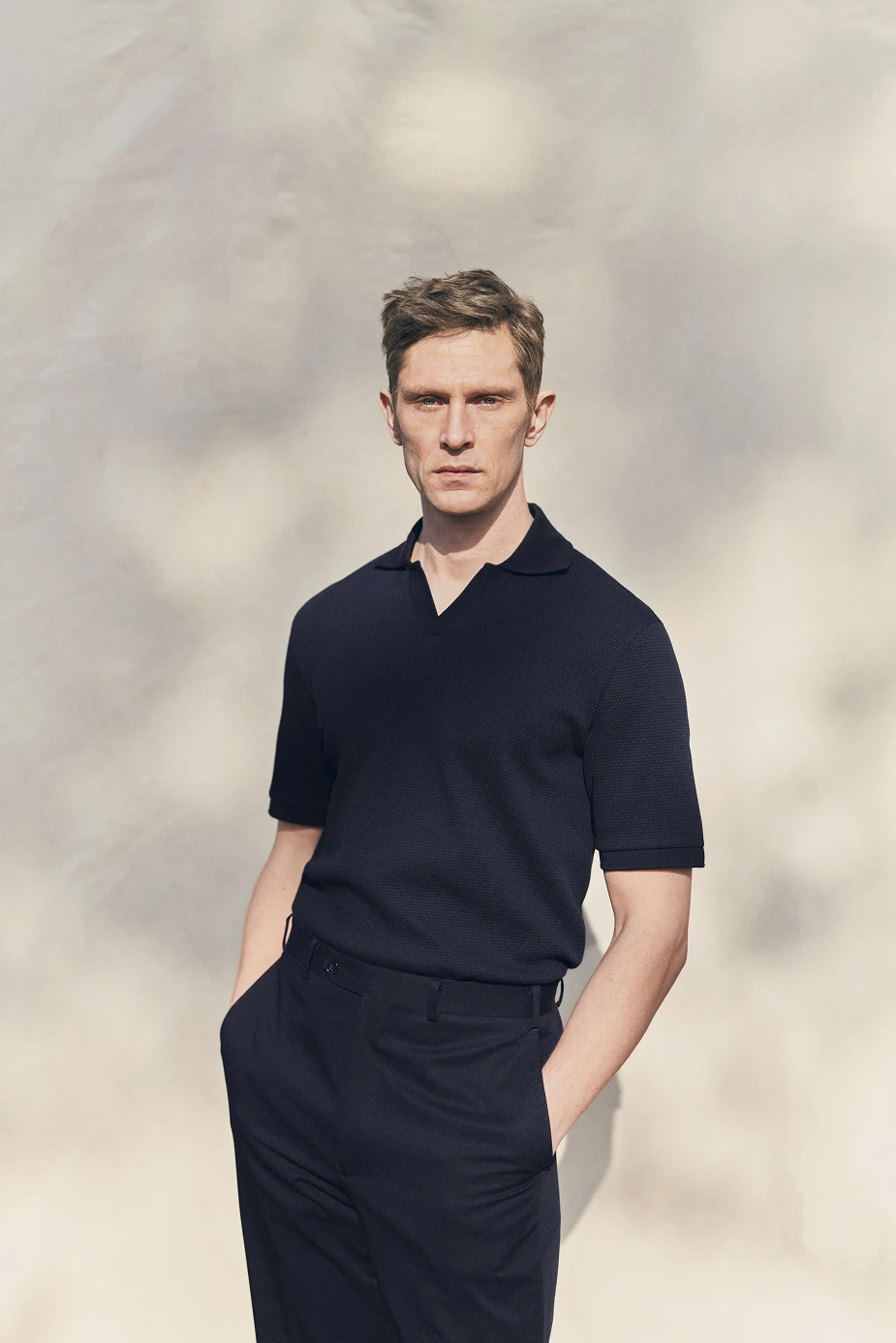 a model posing in a navy polo shirt and navy trousers