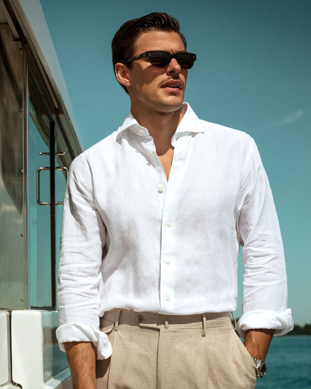 A man wearing A white Eton linen shirt on a boat