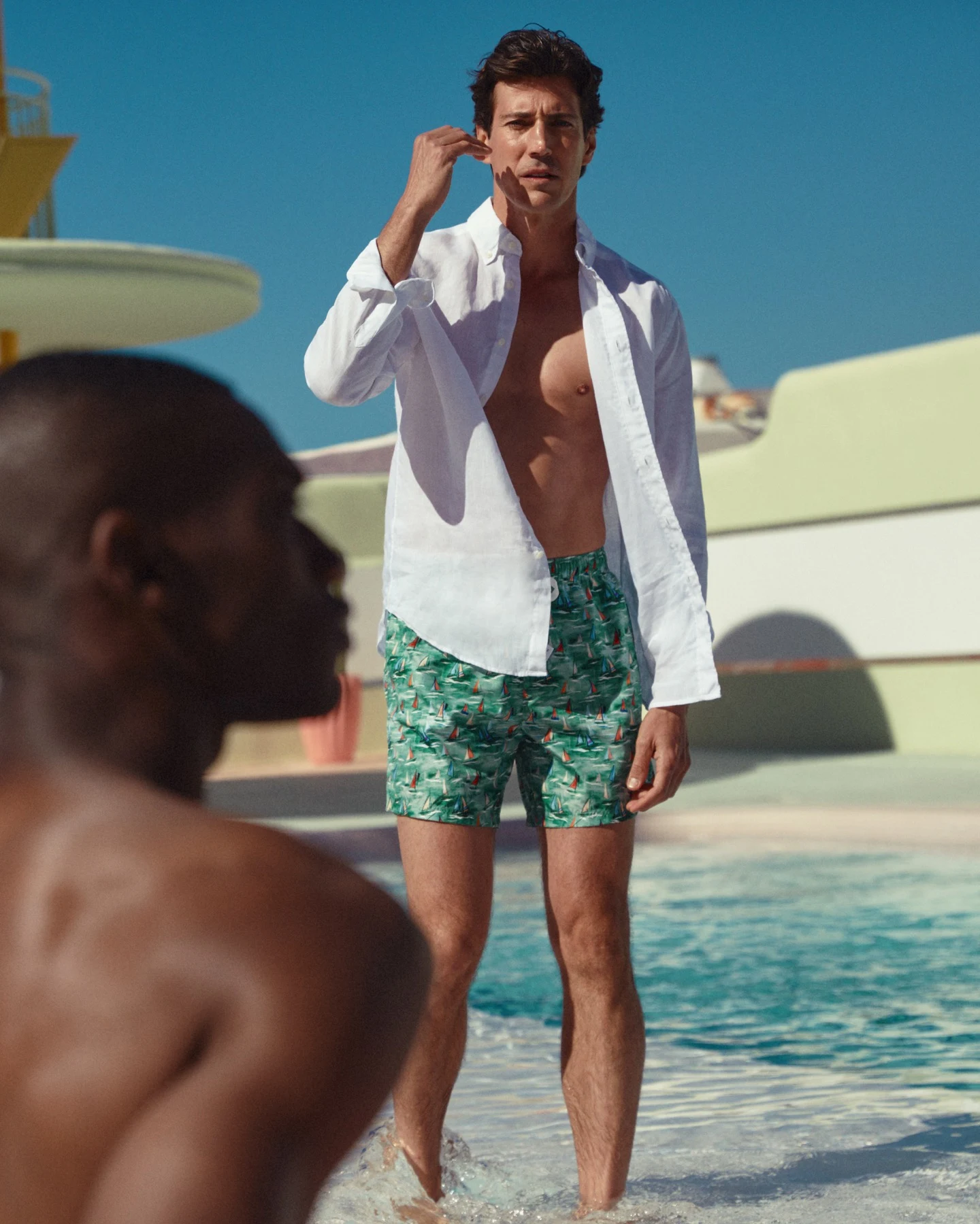 model in white linen shirt and swimshorts