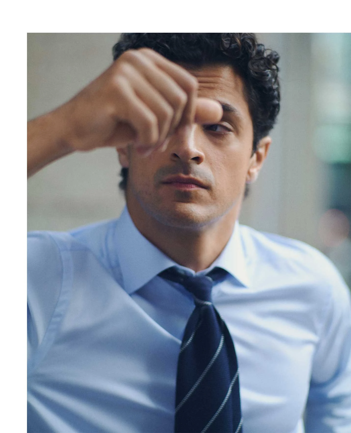 a man touching his head wearing a blue signature twill shirt and a grenadine tie