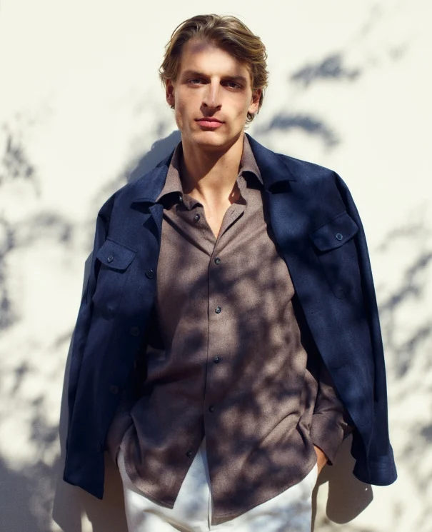 a model posing in the shade of a tree in a shirt and overshirt