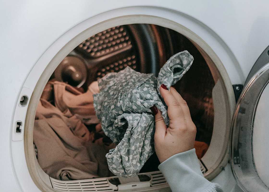Person-lägger-i-tvätt-i-tvattmaskin