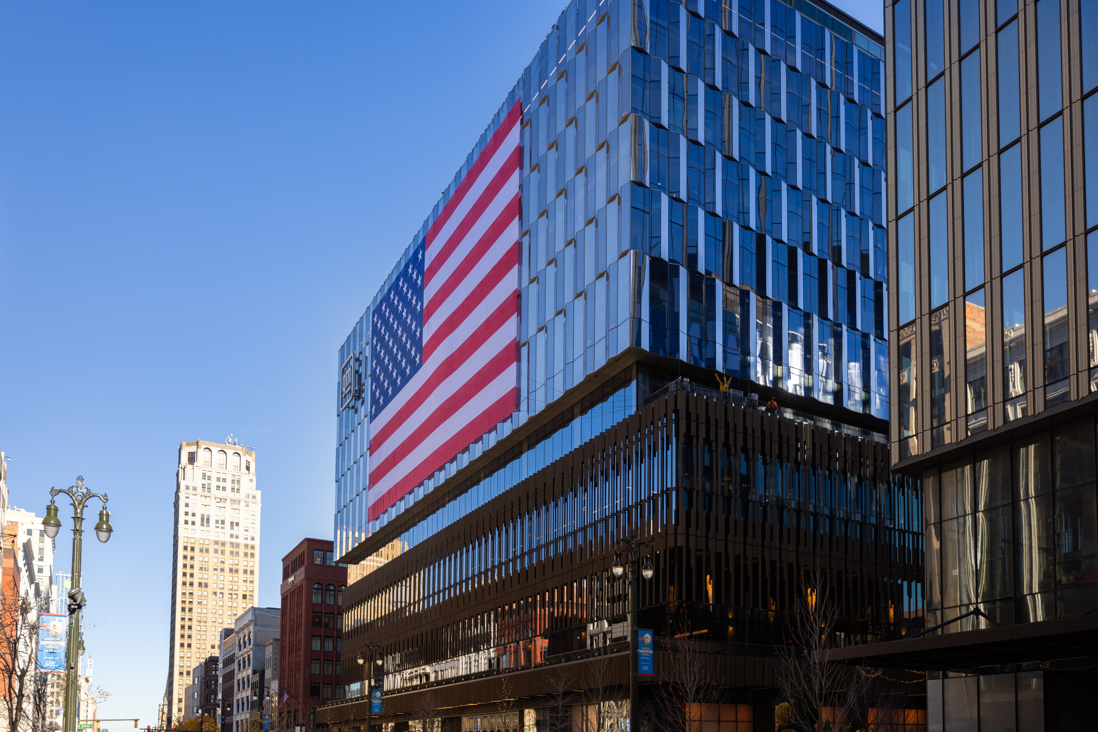 A street-level exterior photo of Hudson’s Detroit with the American flag adorning the facade.