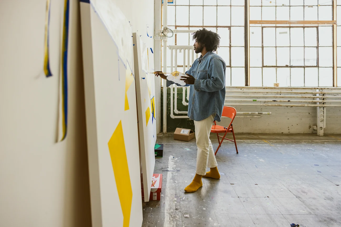 An artist paints in their studio with natural light. 