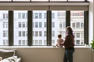 A mother looks out the window with her child. 