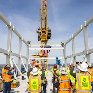 Team members gather to watch the final beam be placed at Hudson's topping off event. 