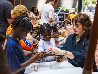 Children making friendship bracelets at Summer Streetscapes. 