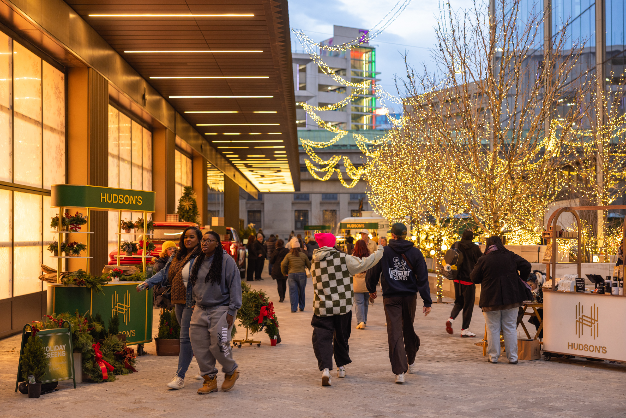 Visitors to Nick Gilbert Way at Hudson’s Detroit for the holiday season, with lit-up trees and other festive decorations in the background.