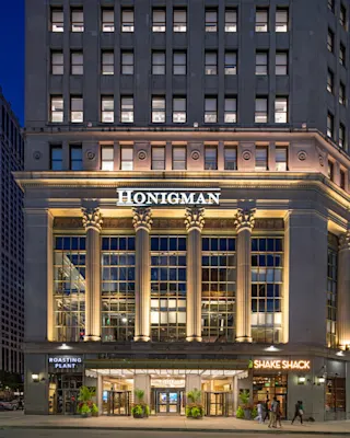 An exterior photograph of the First National Building at night showcasing Honigman branding on the facade.